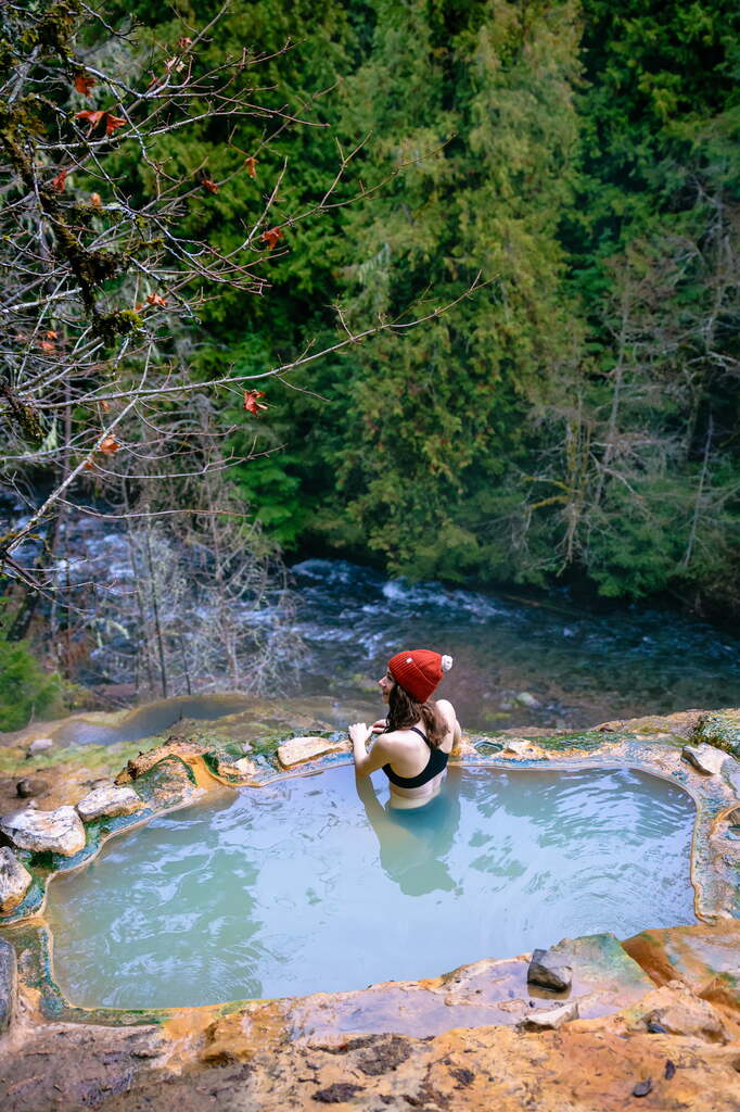 A woman sitting in the hot spring at umpqua hot springs along the highway of waterfalls in Oregon.