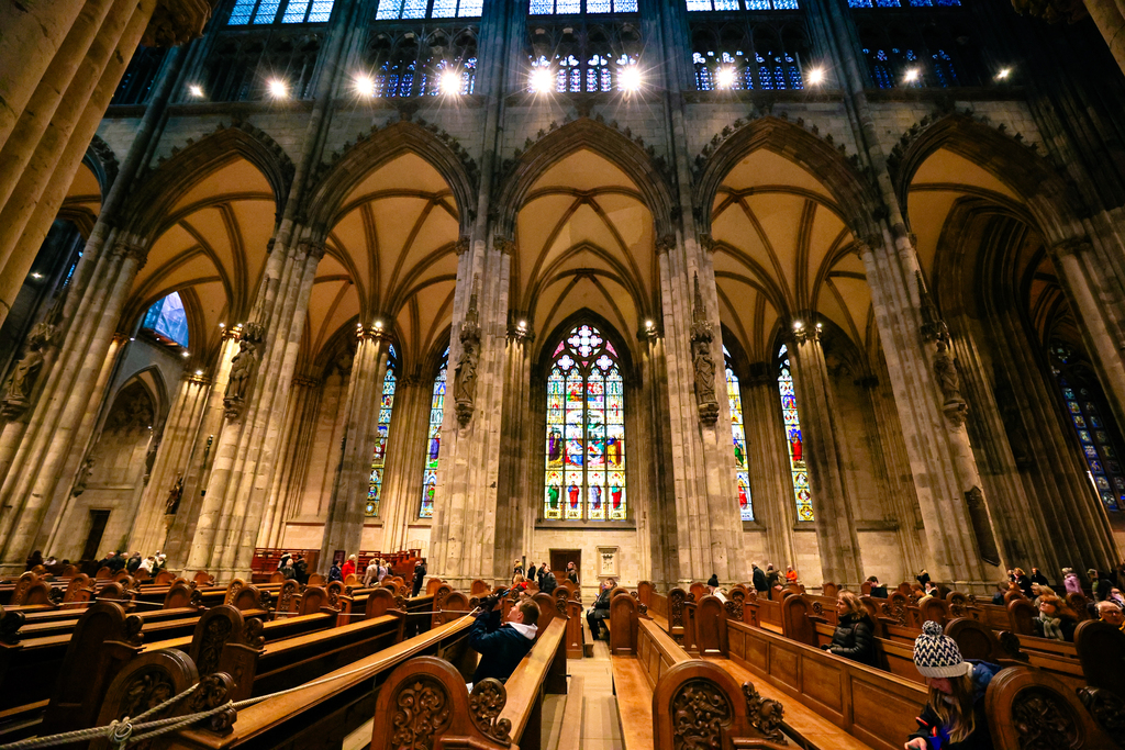 The inside of the cathedral in cologne, Germany with pews and stained glass windows
