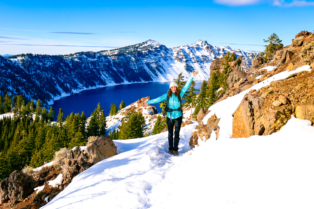 Gwyneth standing along the trail to garfield peak in crater lake national park wearing winter clothing and snowshoes. Visiting crater Lake National Park in winter.