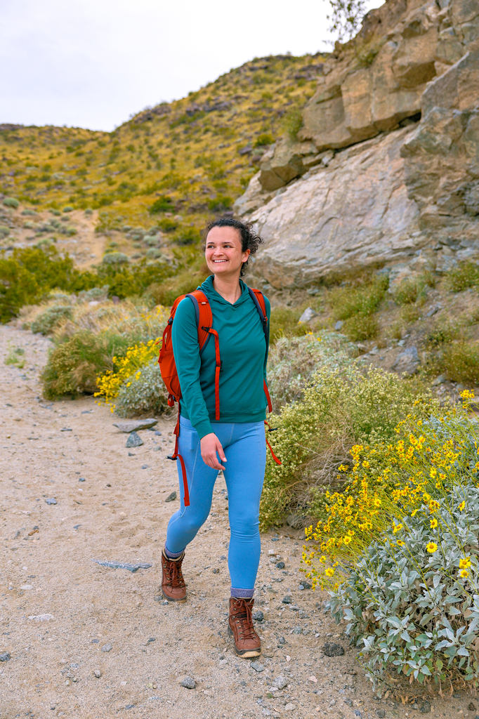 Woman in bright outdoor clothing hiking the Jane’s Hoffbrau Oasis Trail in Palm Springs California with spring wildflowers in the background