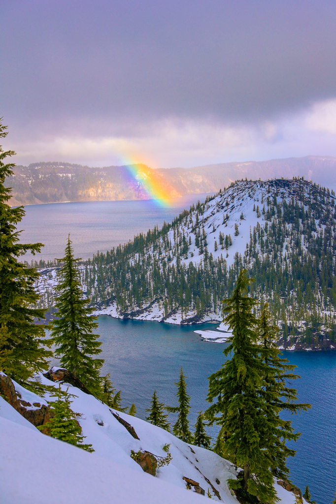 Visiting crater Lake National Park in winter. Wizard island in the snow with a rainbow and fog.