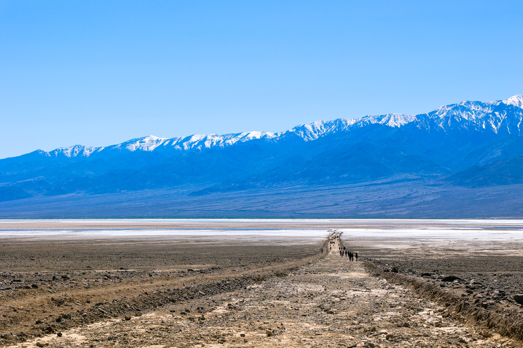 The road out to Devil's Golf Course in Death Valley National Park, California. Image features unique salt structures and water.