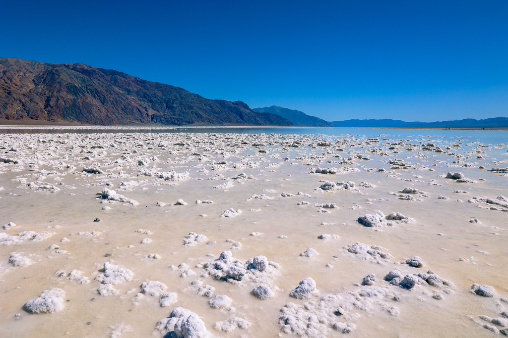 Devil's Golf Course in Death Valley National Park, California. Image features unique salt structures and water during a rare lake in death valley in spring 2024.