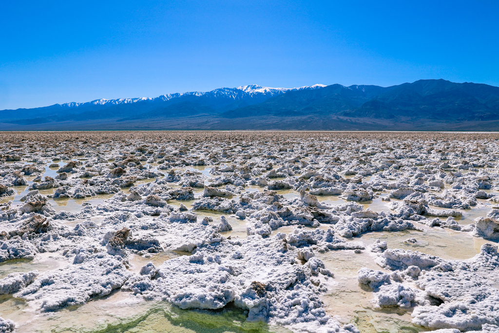 Devil's Golf Course in Death Valley National Park, California. Image features unique salt structures and water.