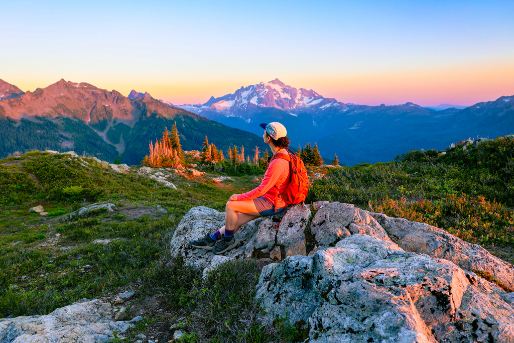 woman on a hike looking at Mount Shuksan at sunset as seen from the yellow aster butte trail in Washington in the pacific Northwest cascade mountain range