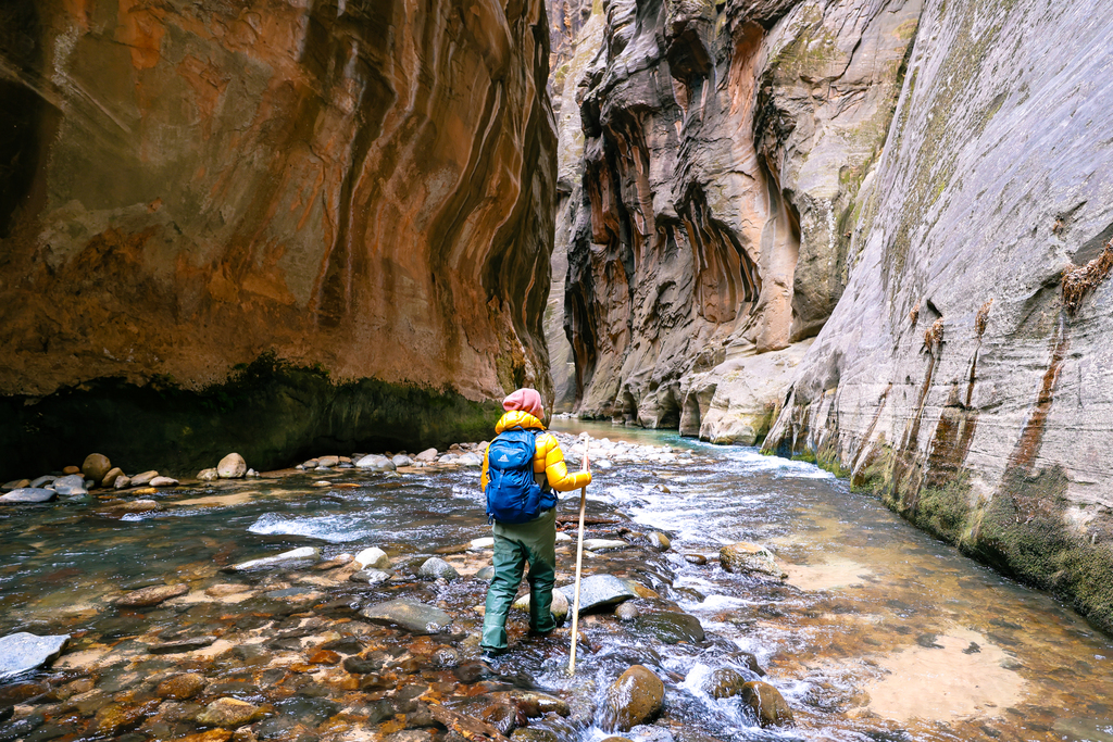 Woman hiking the wall street section of the narrows in zion national park