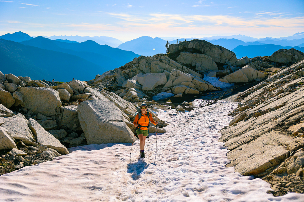 Woman hiking a snow field along the Hidden Lake Lookout hike in summer in Washington state North Cascades National Park