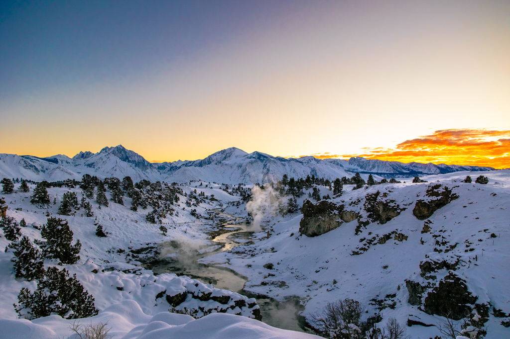 Hot creek geological site with snow in winter sunset